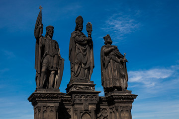 Antique statue of Saints Norbert of Xanten, Wenceslas and Sigismund on the medieval gothic Charles Bridge in Prague built on the 15th century