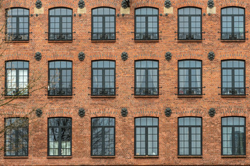 Fototapeta na wymiar Żyrardów, Poland. Window with iron frame and red bricks wall of old factory.
