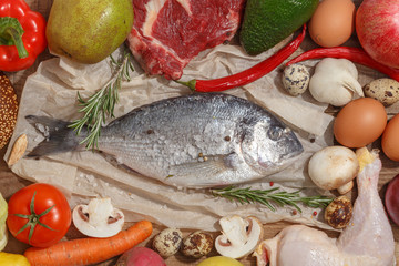 Healthy food clean eating selection: fruit, vegetable, seeds, fish, meat, leaf vegetable on wooden background. Top view.