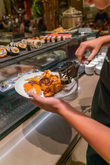 Vertical photo of customer choosing foods in the hotel buffet