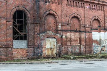 Fototapeta na wymiar Żyrardów, Poland. Front wall made of red bricks with iron frame window of old factory.