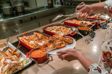 Woman hand choosing delicious Grilled Lobster in the luxury buffet