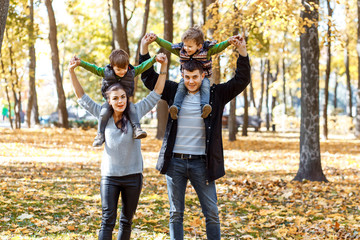Natural pictures of a happy family of four having fun outsiade on a sunny autumn day. Togetherness and happiness concept