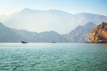 Charming view of the mountains and the sea in the haze near the Musandam - obrazy, fototapety, plakaty