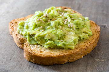 Toasted breads with avocado and sesame seeds on wooden table