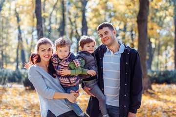 Natural pictures of a happy family of four having fun outsiade on a sunny autumn day. Togetherness and happiness concept