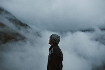 Man wearing hat above the clouds in the mountains