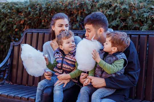 Natural photos of happy family resting in the park eating sugar floss and having fun. Love and togetherness concept