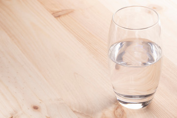 Image of a glass half full of water standing on a wooden table