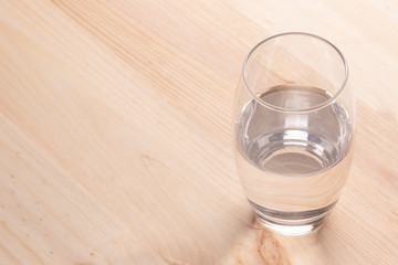 Image of a glass half full of water standing on a wooden table
