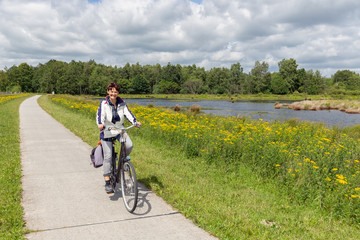 Fototapeta premium Biking woman in Dutch national park with forest and wetlands