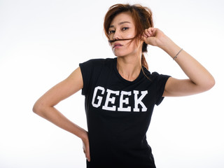 Studio shot of young Asian geek girl playing with her hair as mu