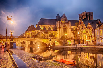 Saint Michael's bridge and old medieval buildings at twilight in historical center of Ghent, Belgium.