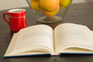 Cup of coffee with open book background.