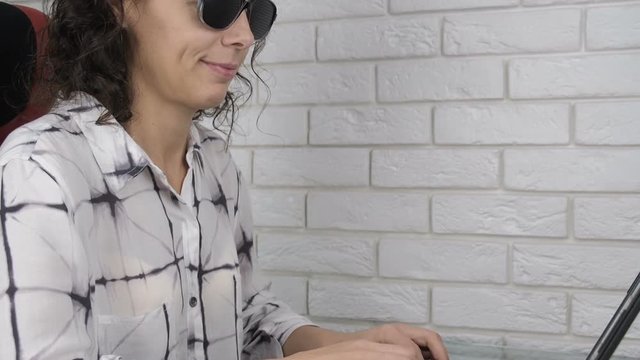 Woman working on computer with pinhole glasses. Woman behind a laptop wearing Oskura glasses.