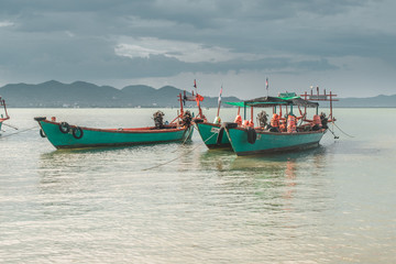 Fototapeta na wymiar Blue wooden fishing boats in calm tropical turquoise water near Rabbit Island in Cambodia