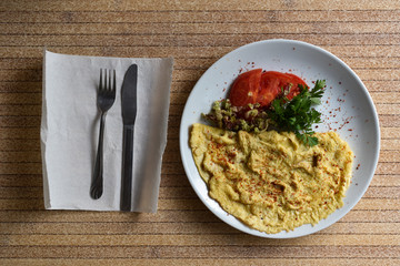 Turkish omelette with tomatoes and parsley on table