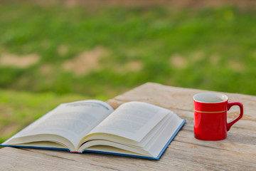Cup of coffee with open book on wooden background