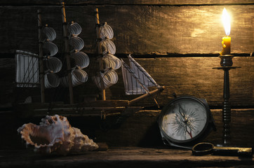 Marine ship, compass, seashell and burning candle on captain table. Sea travel background. Pirate...