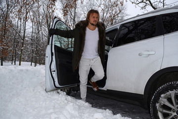A young man leaves the car in the Park winter.
