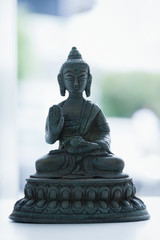 Lord Buddha bronze statue on white display. Buddhism religion decorative figurine with cold blue effect applied