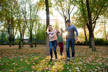 Naklejka na ściany i meble Family of three enjoy autumn park having fun smile
