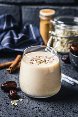 Oatmeal dates cinnamon smoothie on dark background. Selective focus, space for text.