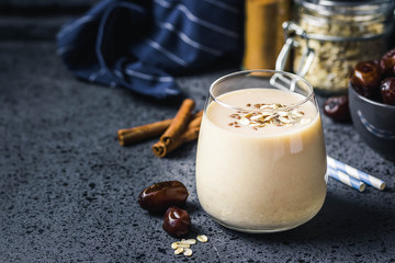Oatmeal dates cinnamon smoothie on dark background. Selective focus, space for text.
