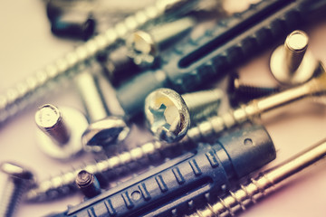 Close up view of fastening elements bolts, nails, screws, washers, konfirmats, dowels blurred on the top and bottom of photo.