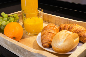 breakfast tray with orange juice croissants and fruit