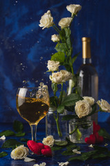Valentines day. Splash of white wine. Romantic evening. Wine, a bunch of white roses and red hearts on a blue background. Holiday of lovers. A delicious alcoholic drink for two people. Picture photo.
