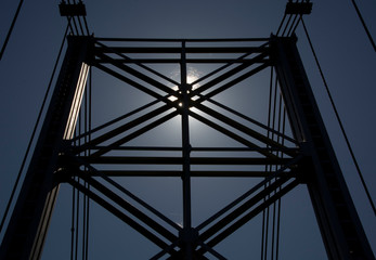 Fototapeta premium Silhouette of metal and cable bridge against the sun