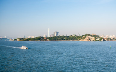 Ferry boat passes island of Gulangyu in foreground with background of Xiamen in China