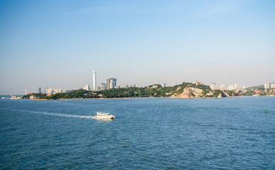 Ferry boat passes island of Gulangyu in foreground with background of Xiamen in China