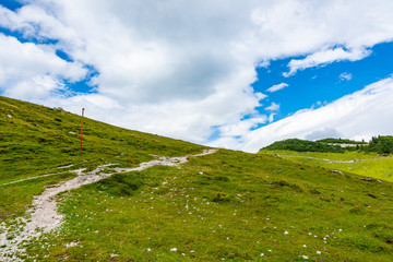 Slovenia mountains near the Kamnik city on Velika Planina pasture land. View of mountains with white clouds and blue sky, mist in the hill. Beautiful and tranquil nature, fresh grass