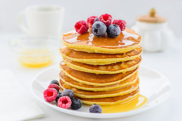 American pancakes with berries and honey on a wooden table