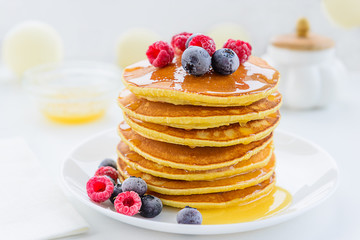 American pancakes with berries and honey on a wooden table