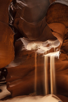 Sand falls from the sandstone shelves in a canyon
