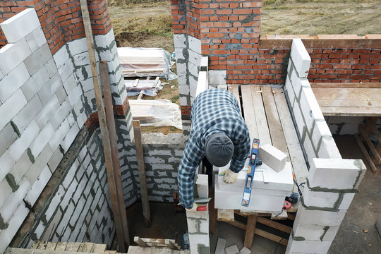The master, using a trowel, glues gasblocks with a glutinous solution at the construction site