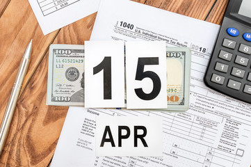 Day of pay tax. Date of 15th april on table with tax form, calculator and money. Top view.