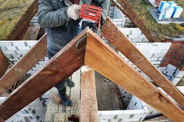 Workers cut the rafters on the roof of the chainsaw house