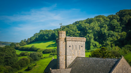 Old English norman, romanesque church, tower of a castle in a green hilly landscape on a summer sunny day with blue sky in the UK in a holiday Dorset countryside between Sidmouth and Lyme Regis.