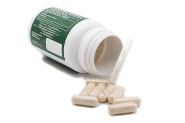 Pills spilling out of pill bottle on a white background