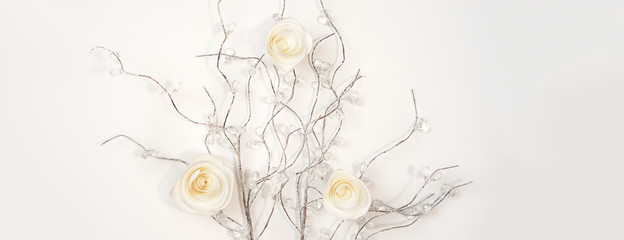 White paper Roses on silver branches on white background. Flat lay, top view. Valentine's Day background, horizontal