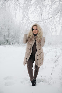 Image of happy blonde woman on walk in winter forest