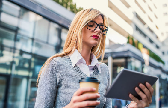 Young business woman drinking coffee and using digital tablet outdoor. Business, education, lifestyle concept