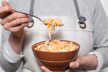Sauerkraut on a fork over a plate in the hands of a woman. 