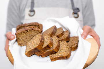 Black rye whole grain bread in the hands of a woman baker. 