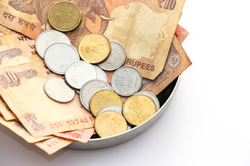 Close up view of donation plate with indian banknotes and coins on white background.