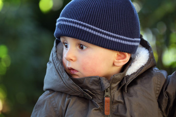 Baby Boy Wearing A Blue Knit Winter Hat And Green Winter Parka